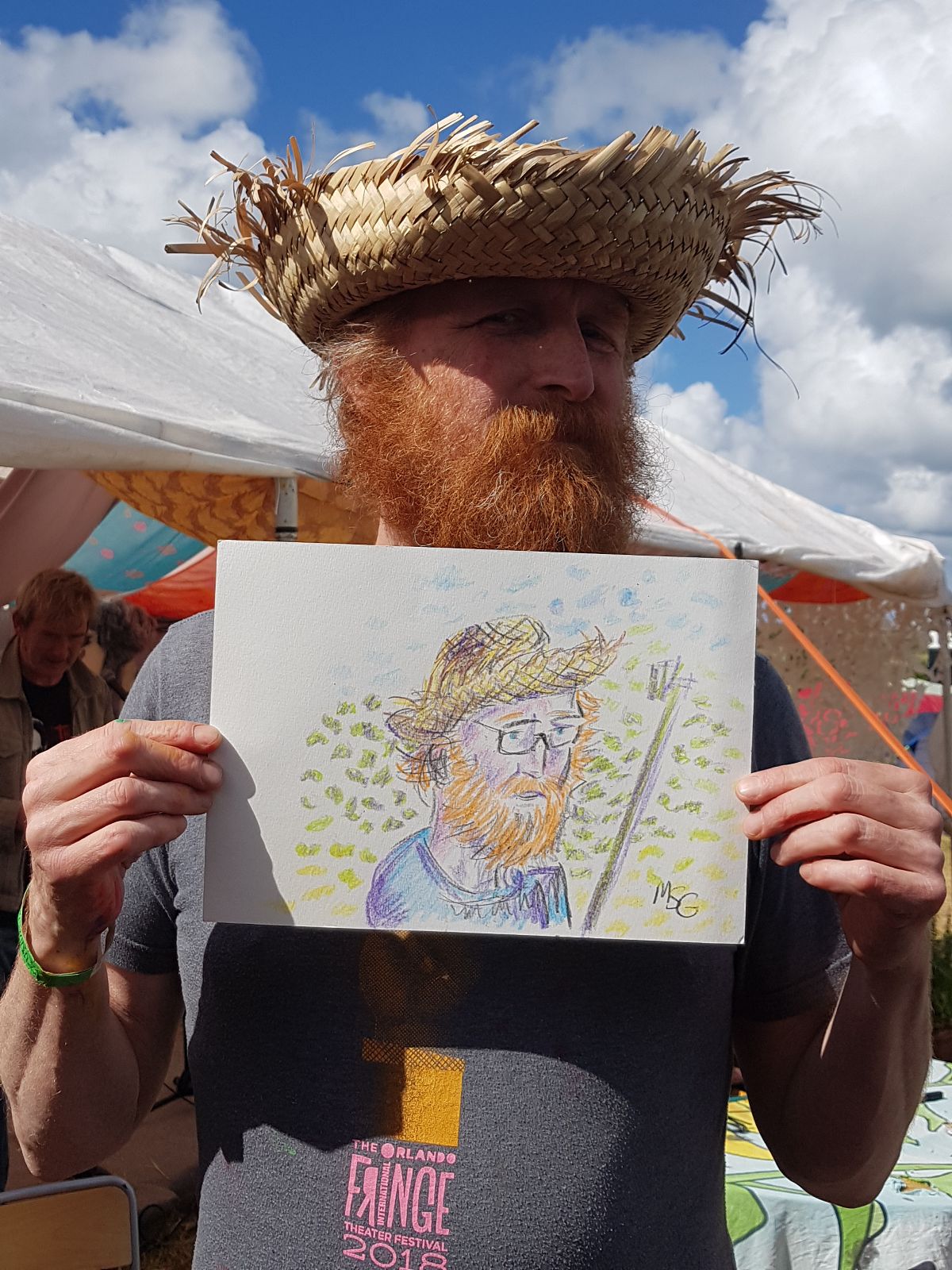 Photo of an actor dressed as Vincent Van Gogh, holding a sketch of himself.