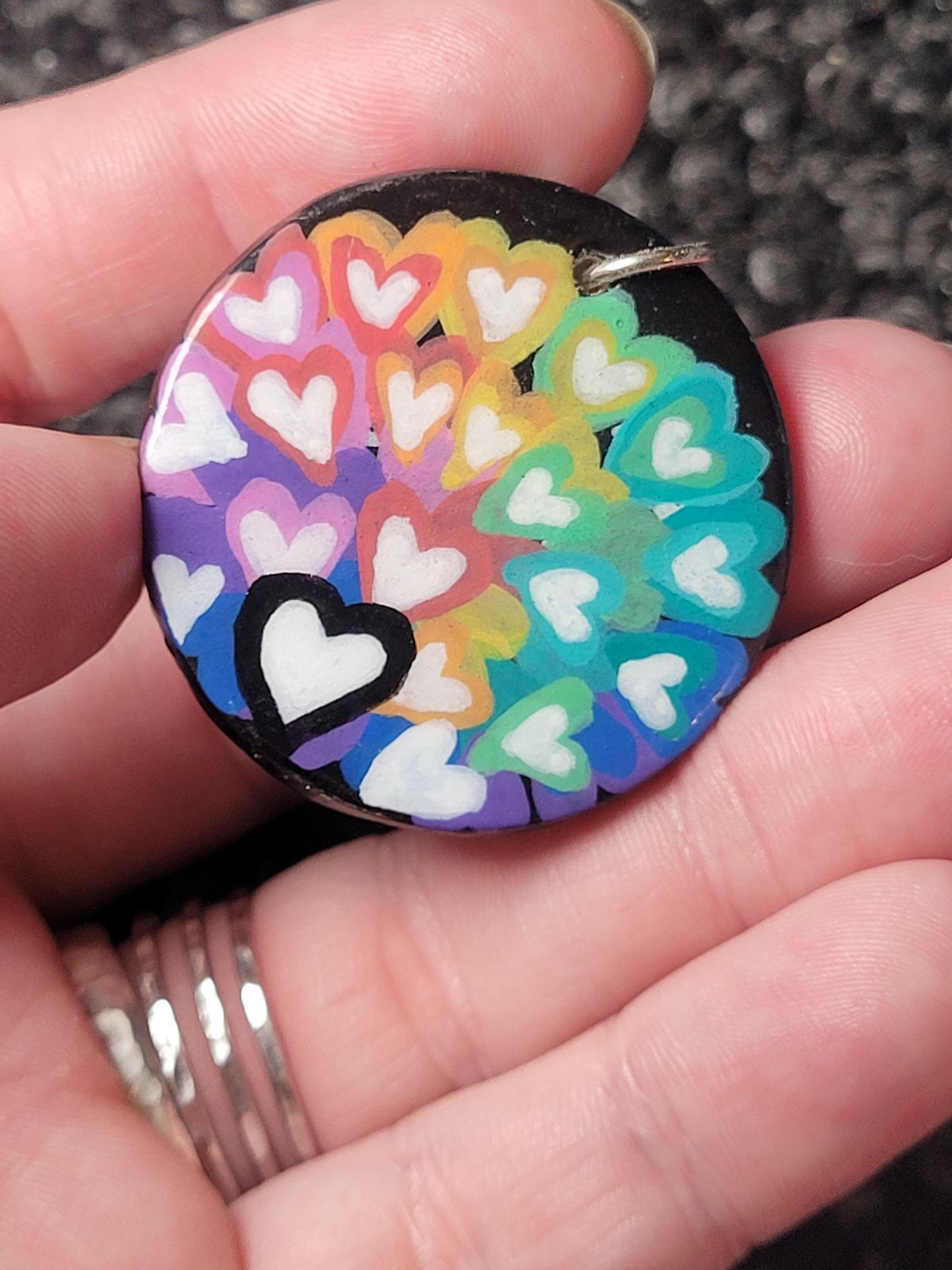 Badge with many hearts in white with outlines in a rainbow of colours