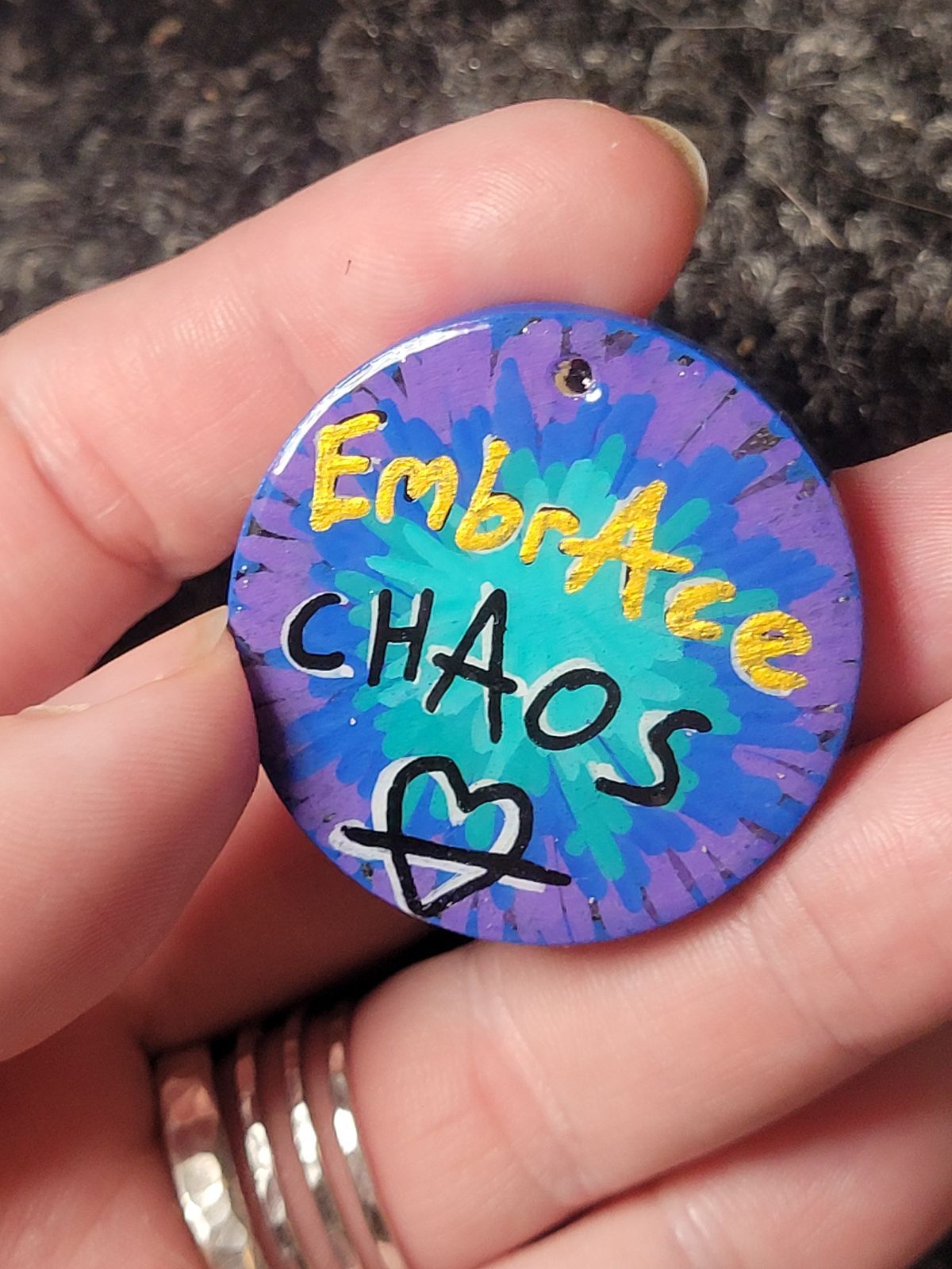 Multicoloured splatter badge reading 'Embrace Chaos' in black, white and gold.