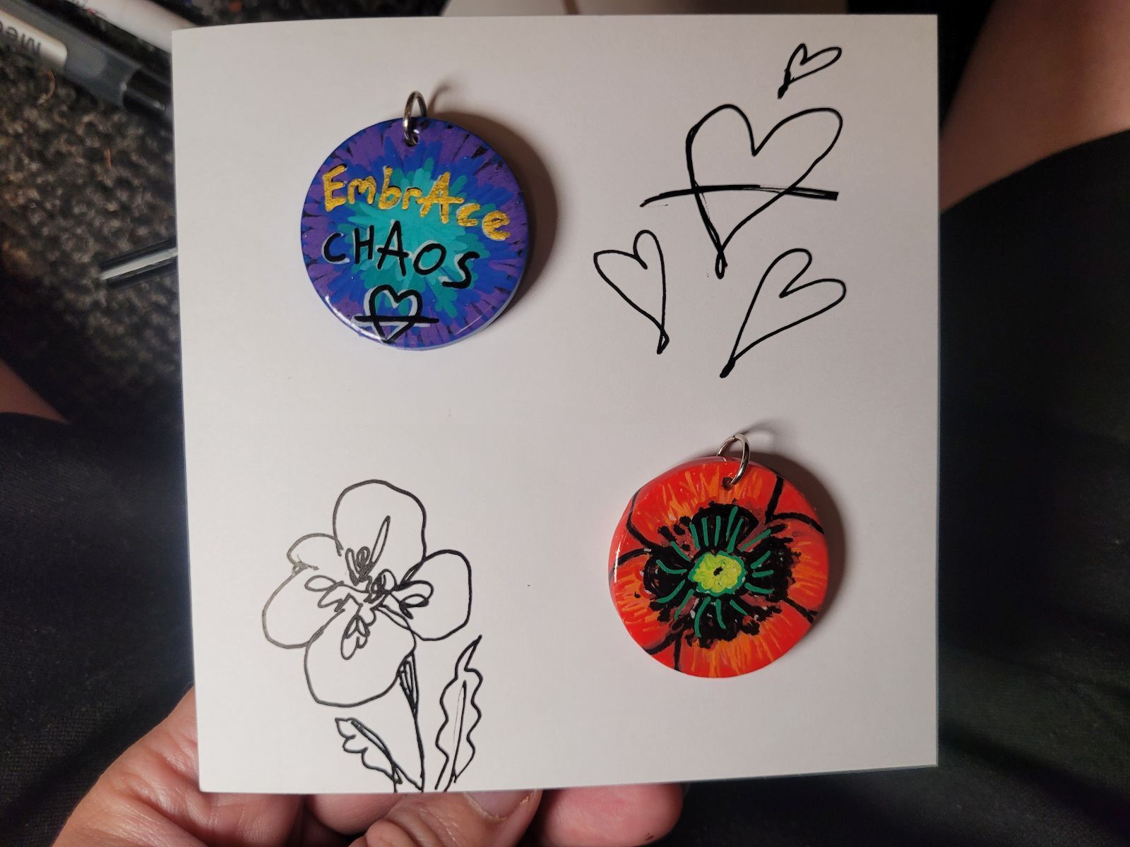 Two badges pinned to a hand drawn gift card with hearts and a poppy sketched on it.