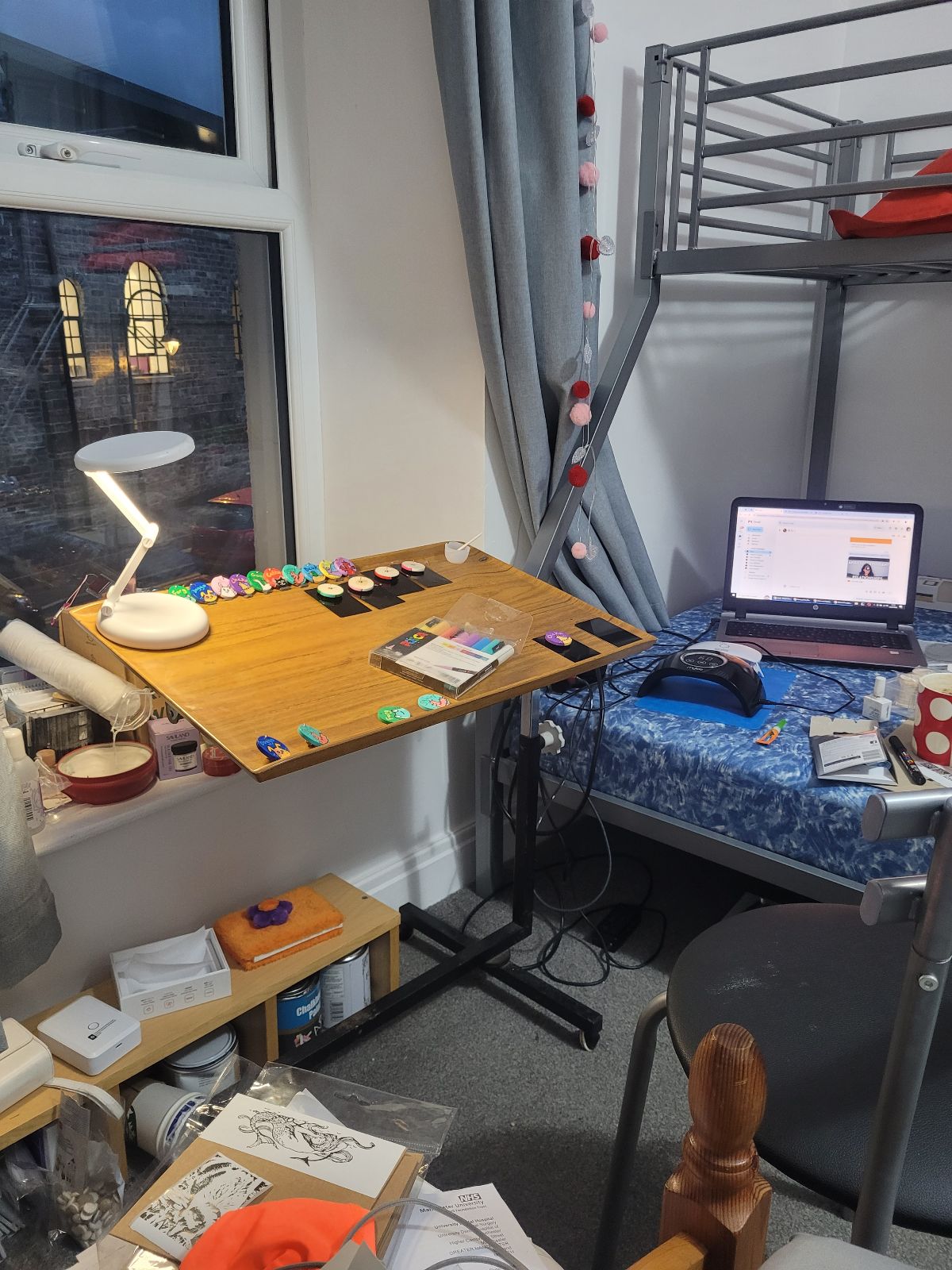 Photo of a rolling table in a bedroom set up with various brightly coloured badges laid out to work on.