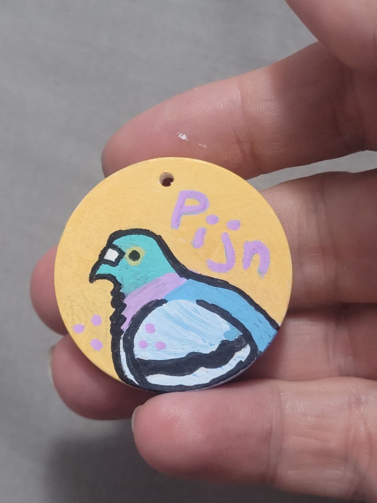 Cute colourful pigeon with the word 'Pijn' above, on an orange background.