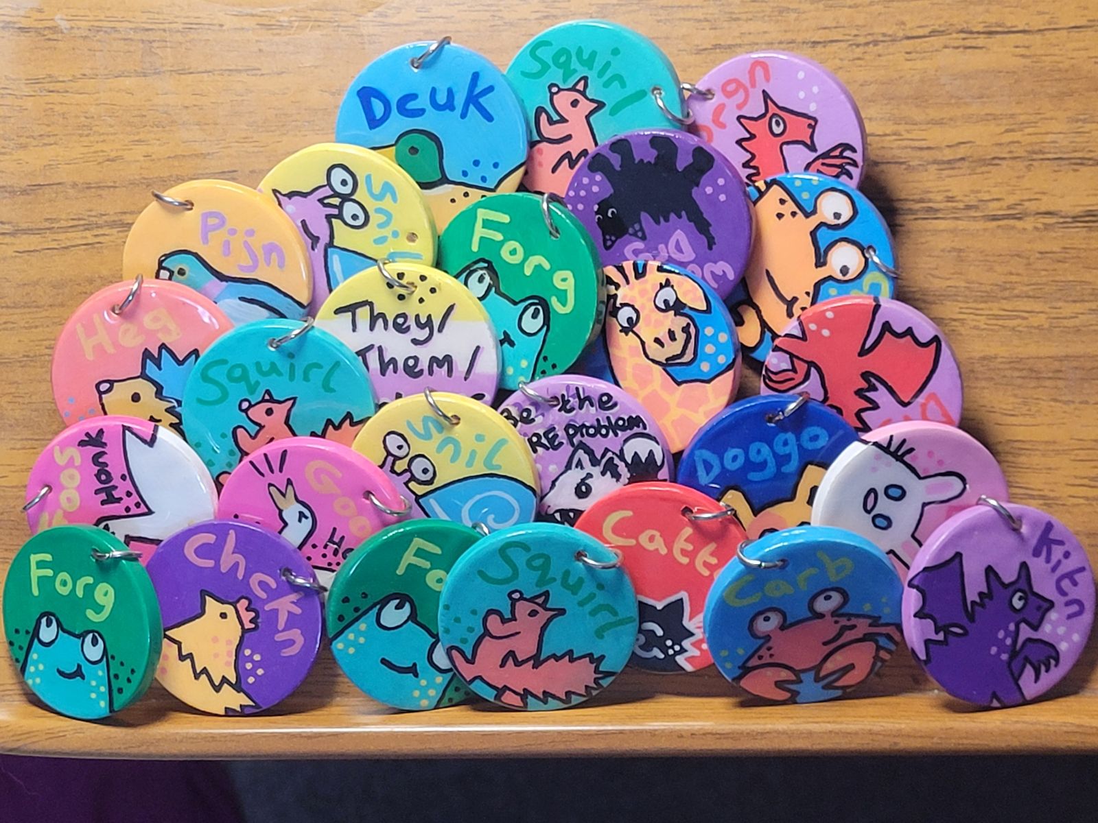 A pile of brightly coloured badges on a wooden background (desk).