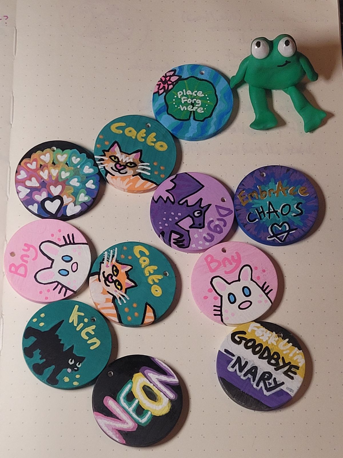 Gift badges include a ginger catto, two pink Bny bunnies, a kitn, a Drgn, one that reads 'Neon' in neon lettering, and an 'embrace chaos' badge, alongside a polymer clay frog.