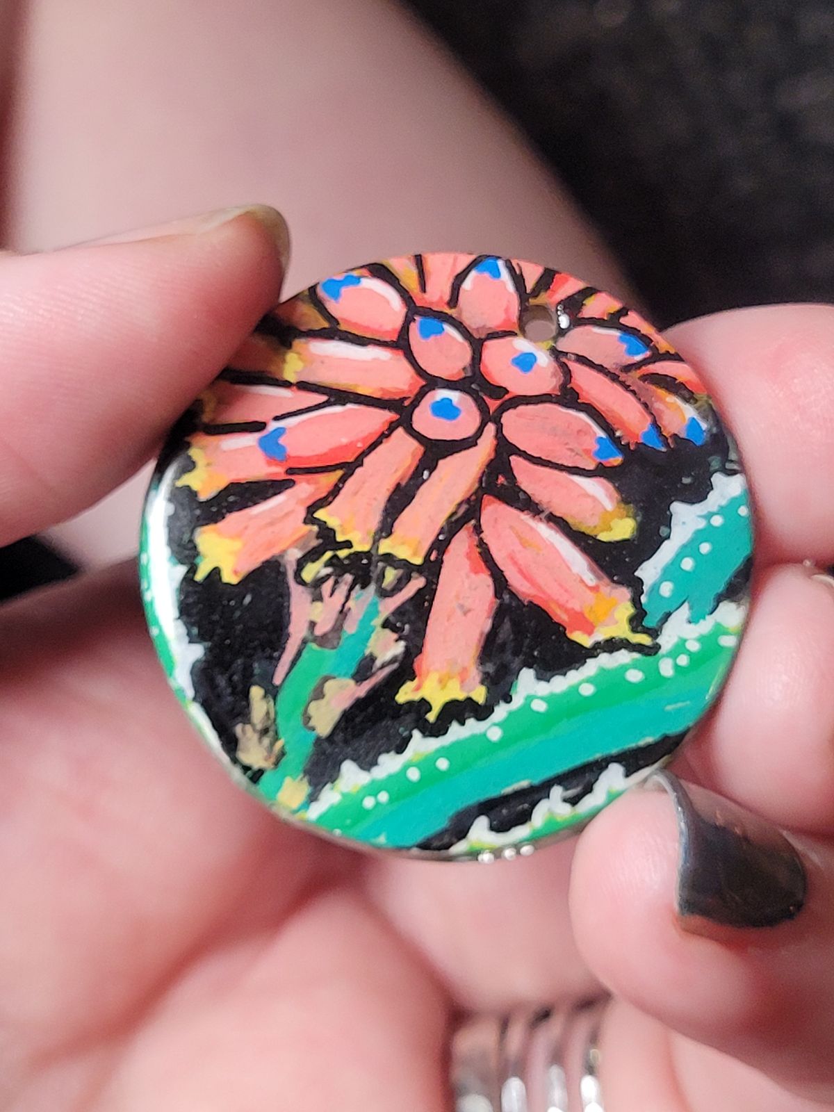 Badge featuring a bright coral coloured aloe flower spike, and spiked aloe leaves.