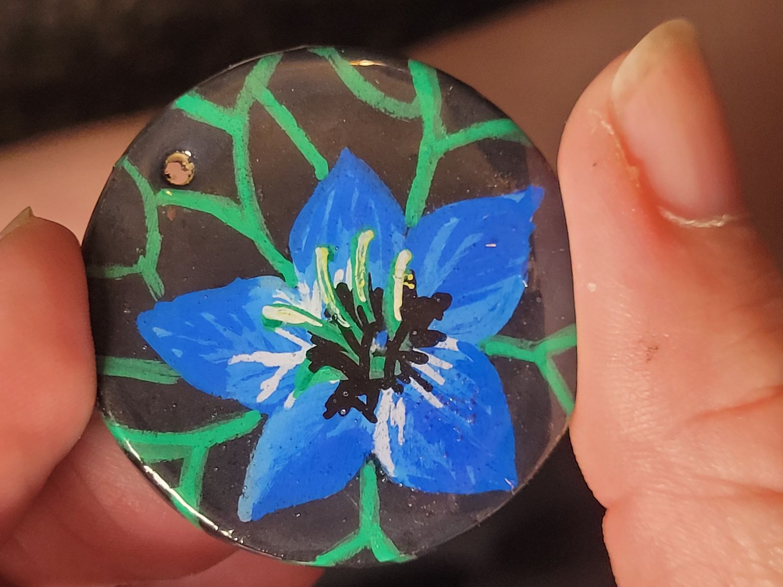 Badge featuring a blue nigella flower and green leaves.