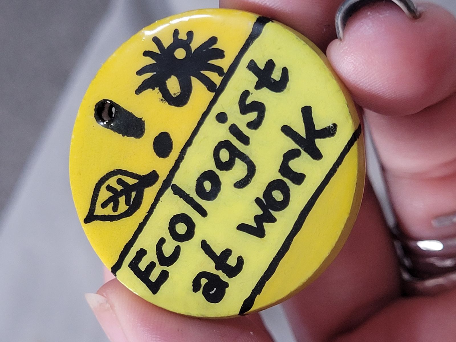 Bright yellow badge with nature symbols and text: Ecologist at Work'