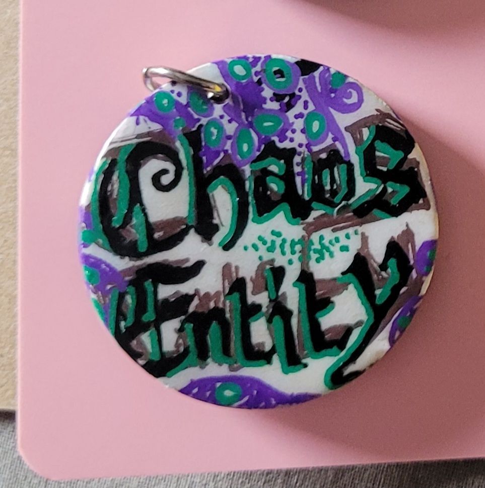 A badge on which the words 'Chaos Entity' are written in gothic style script.