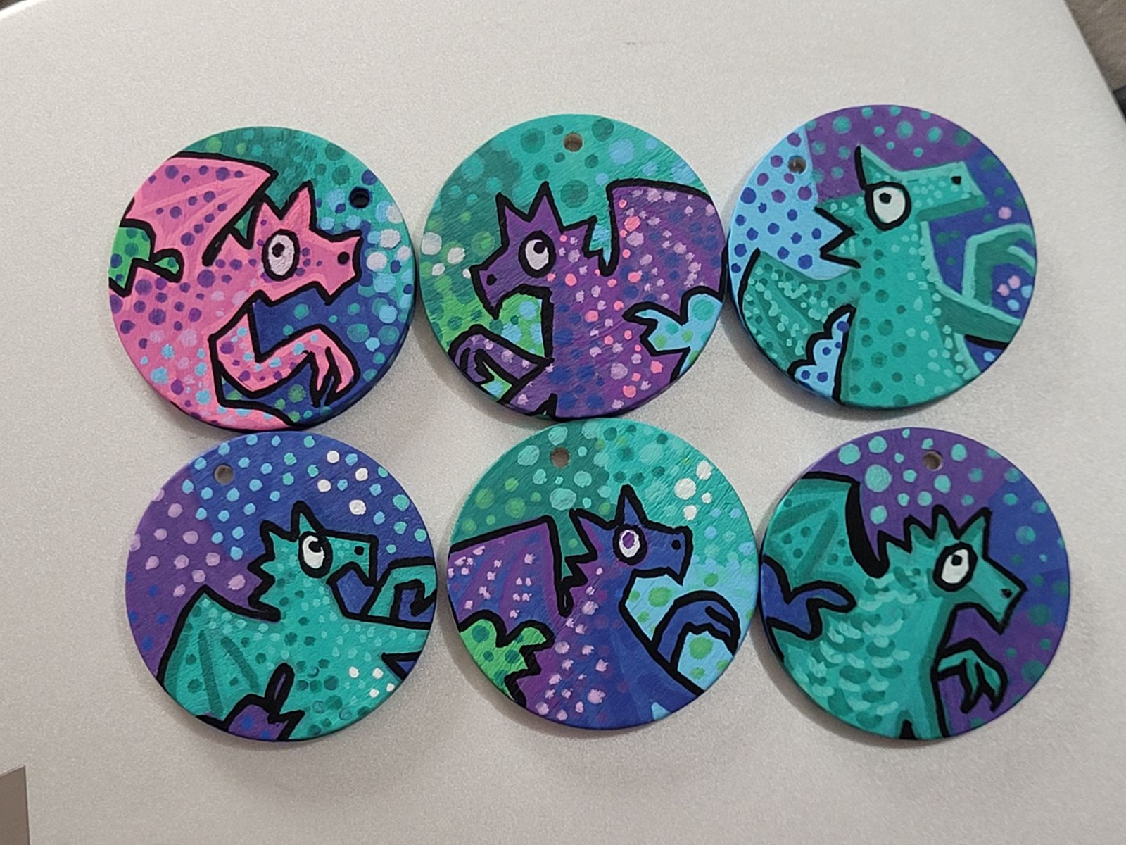 Six cute dragon badges in mixed shades of pink, purple, blue and turquoise.