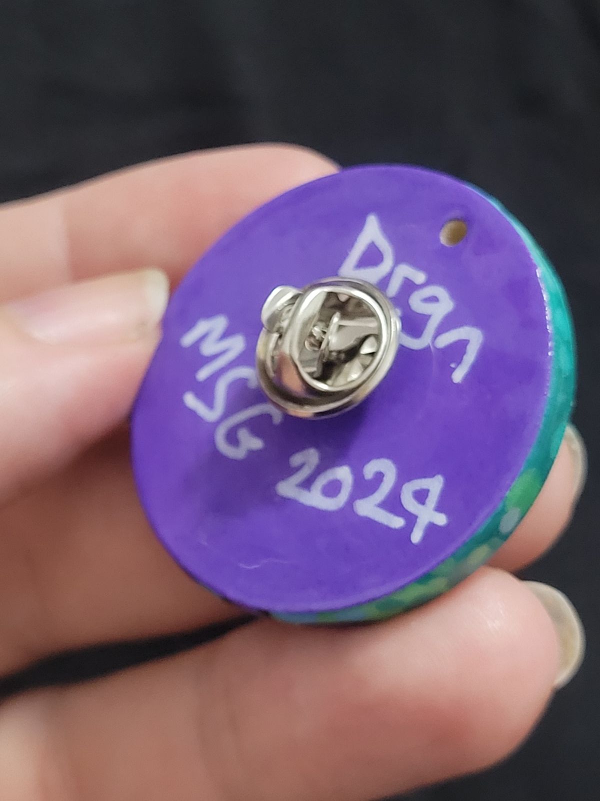 Reverse of the purple Drgn badge, with a purple back that reads 'Drgn' and 'MSG 2024' above and below the badge fixings.