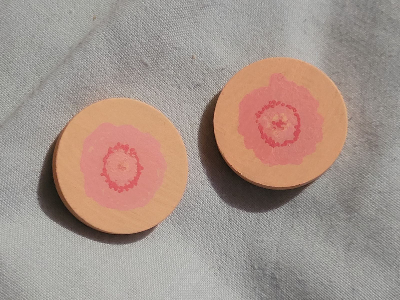 A smaller pair of beige and pink nipple badges.