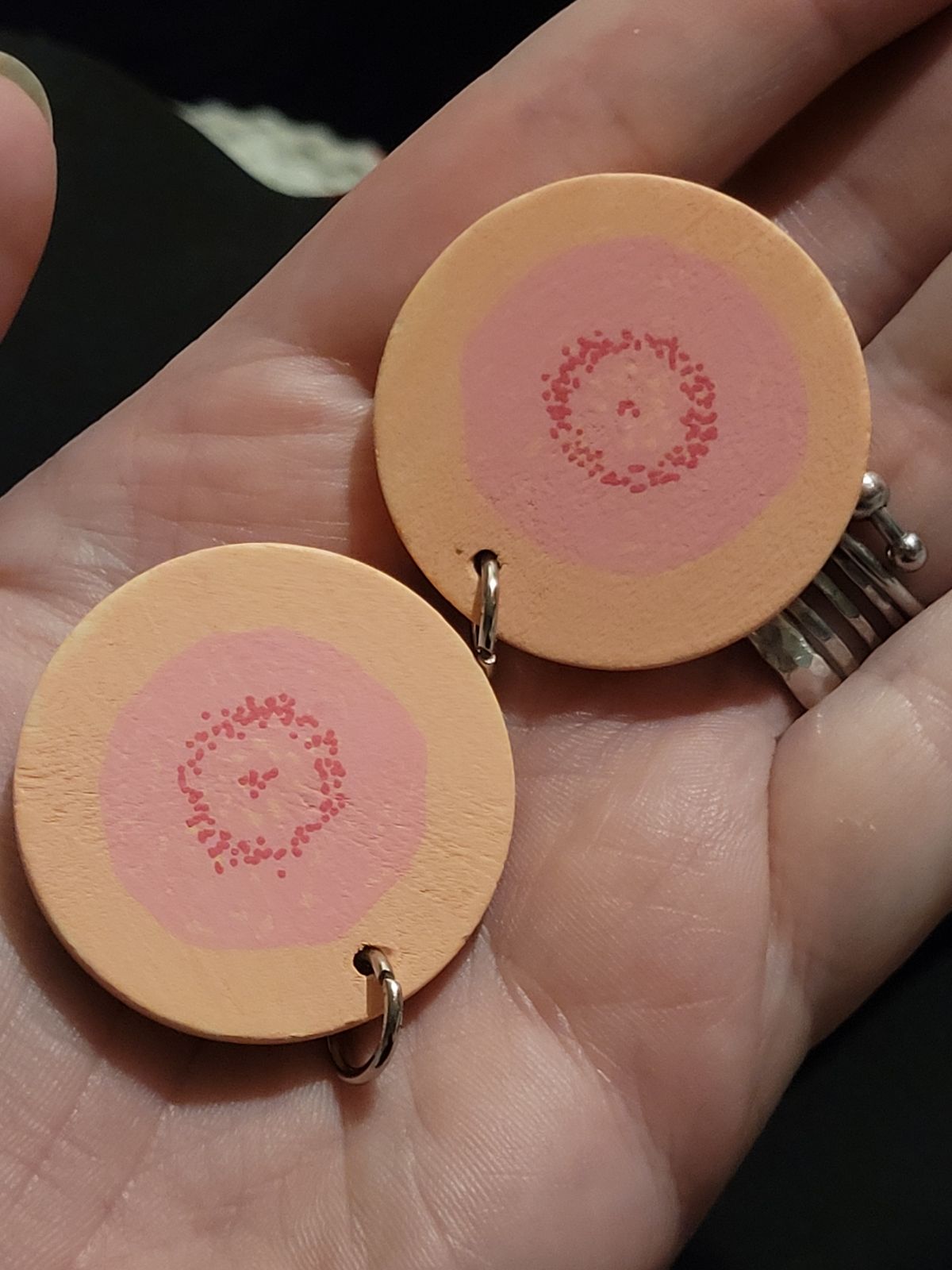 Badges made to look like beige and pink nipples, with a little steel ring attached to each.