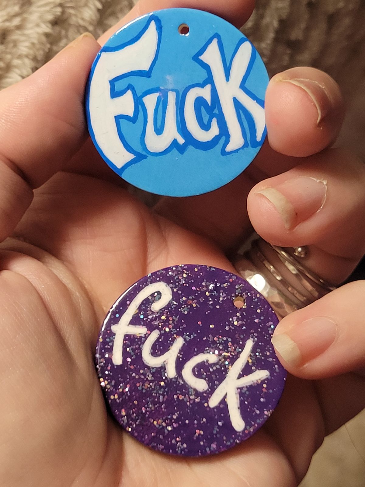 Coloured 'fuck' badges, in blue and sparkly purple