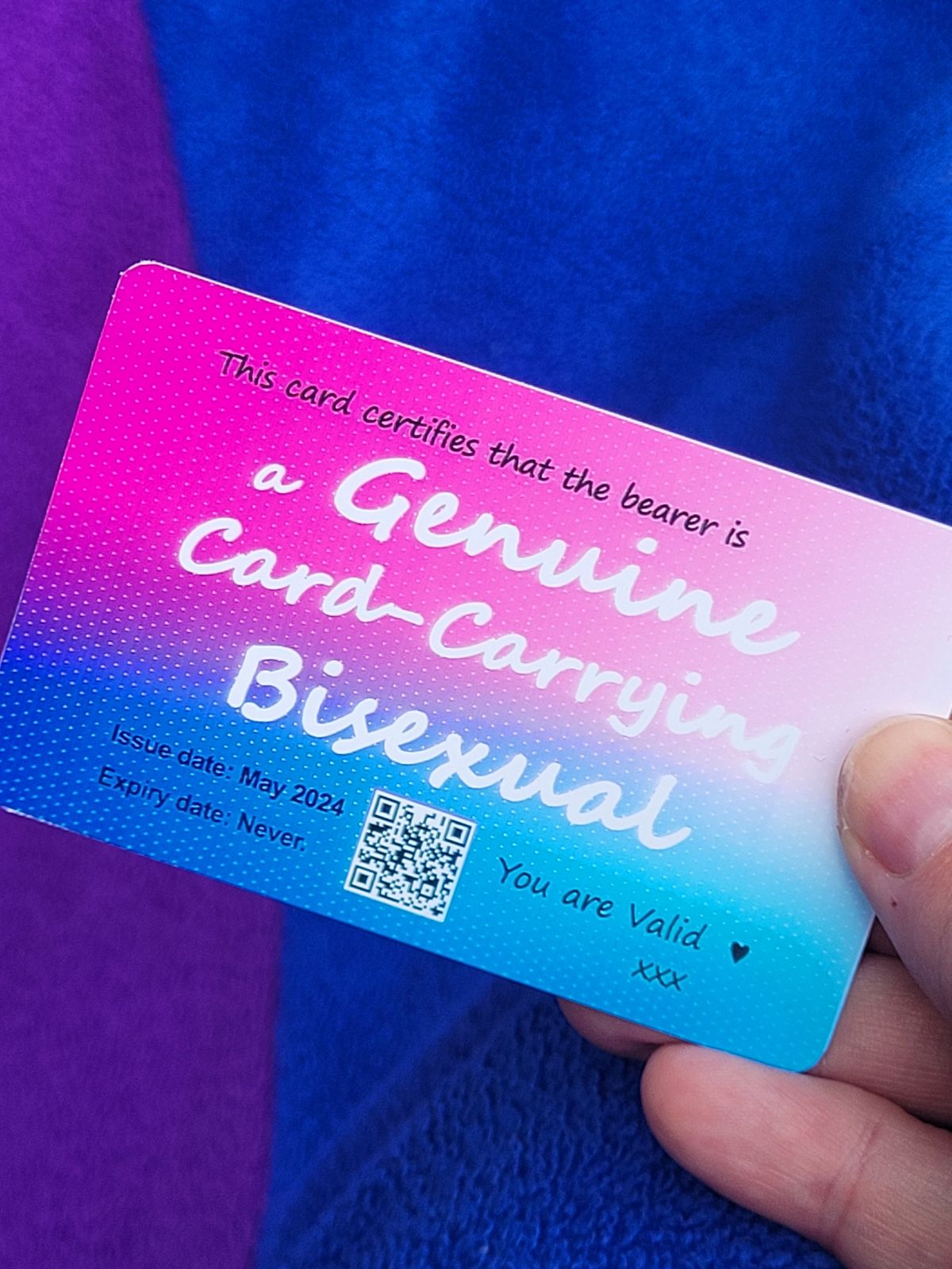 A card with colours shading from pink through purple to blue reads 'This card certifies that the bearer is a Genuine Card-carrying Bisexual' in large text, and 'you are valid' in smaller print.